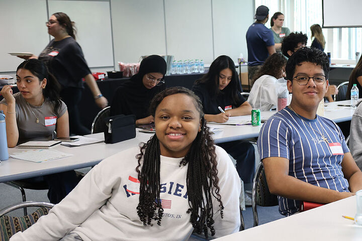 Students sit at tables in a classroom.